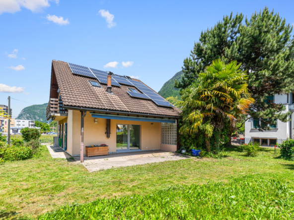 Maison individuelle avec panneaux solaires, toit en pente et jardin verdoyant