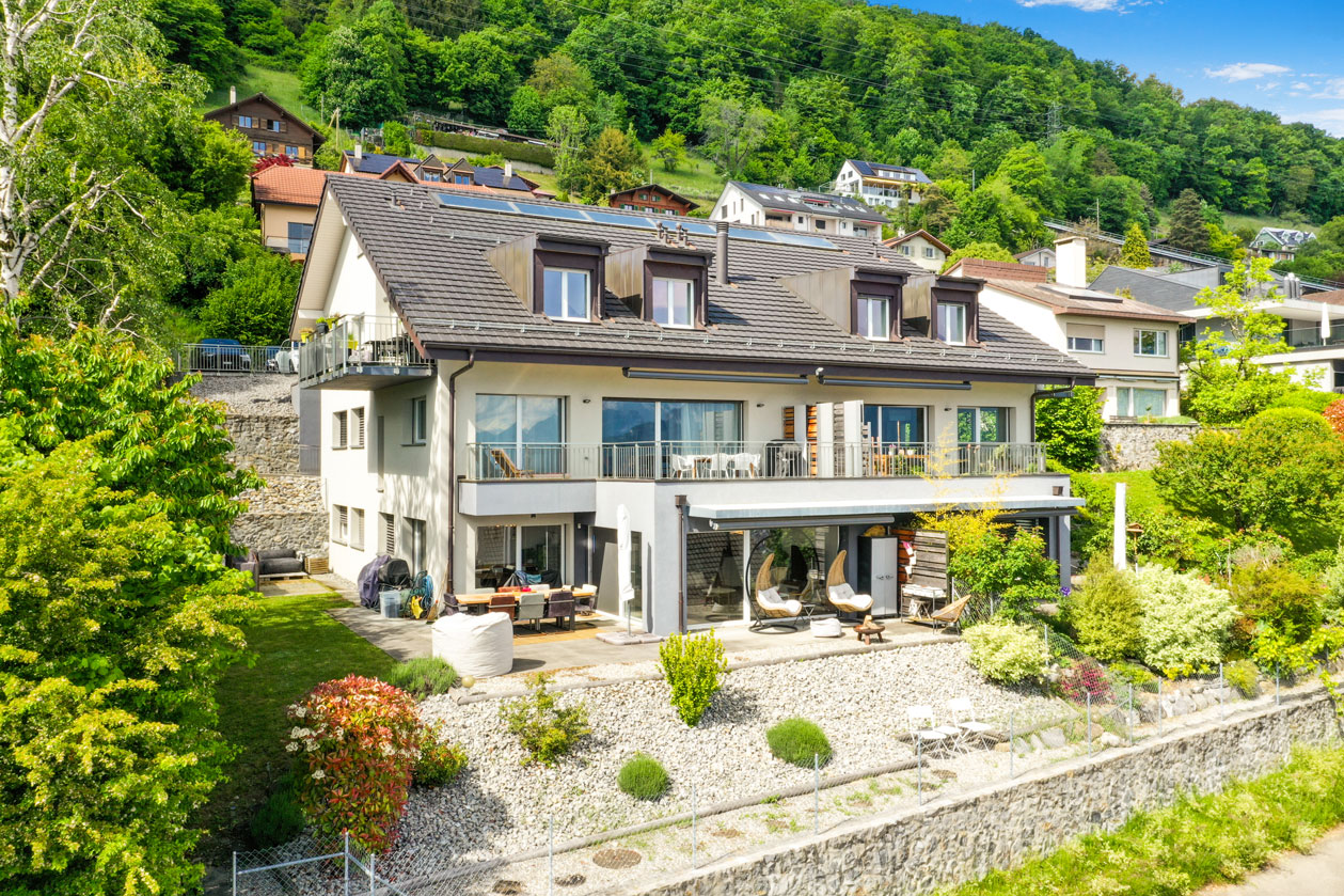 Façade arrière de la maison à Chardonne avec terrasses, verdure et balcons