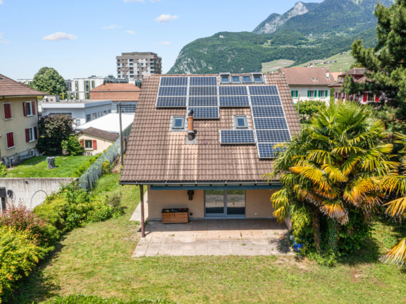 Toiture de maison équipée de panneaux solaires en environnement urbain et montagneux