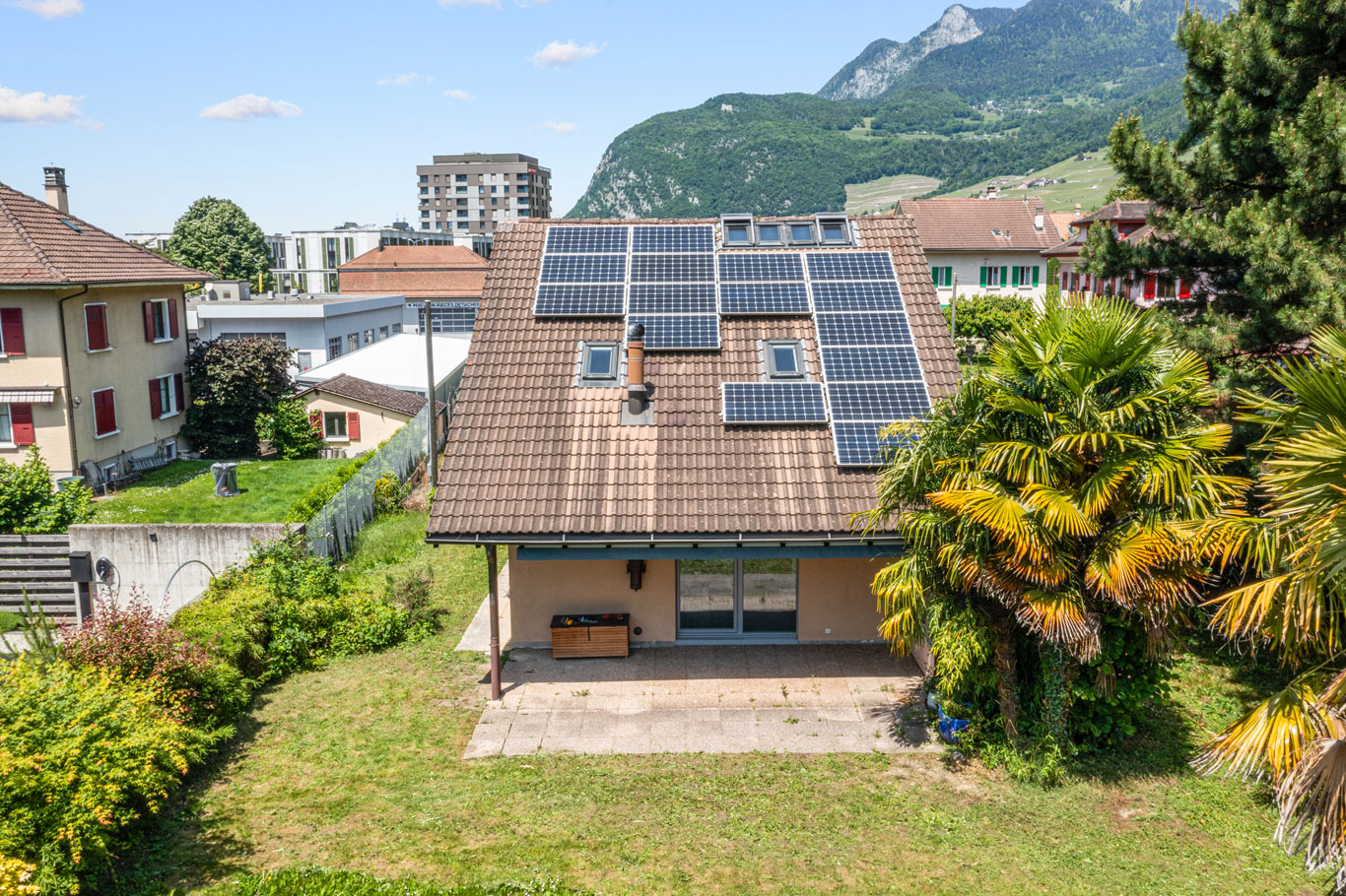 Toiture de maison équipée de panneaux solaires en environnement urbain et montagneux