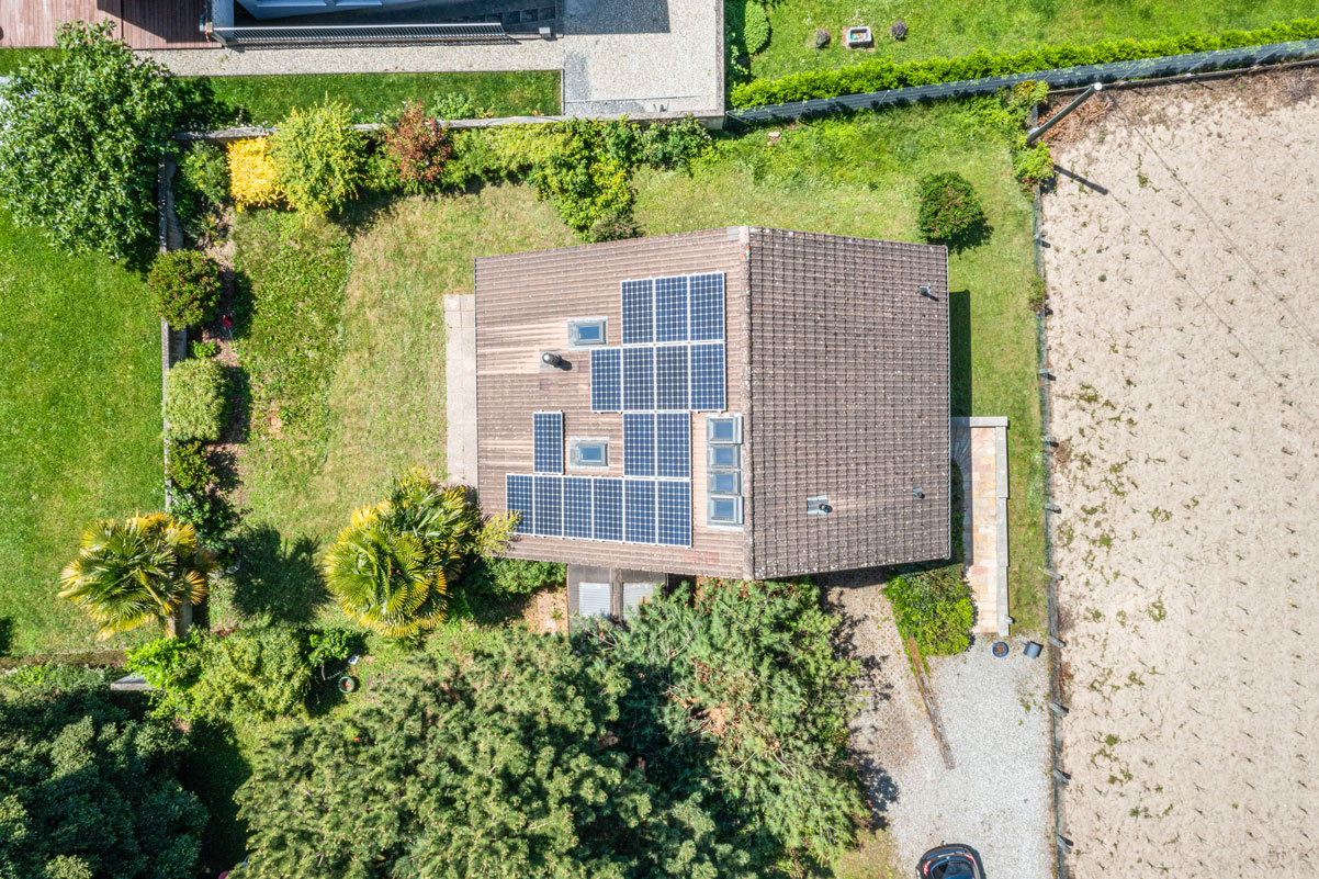 Vue aérienne verticale d’une maison avec panneaux solaires et jardin arboré