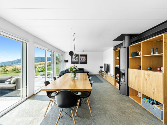 Salle à manger moderne avec grandes baies vitrées donnant sur la terrasse et le jardin, décorée dans un style épuré.
