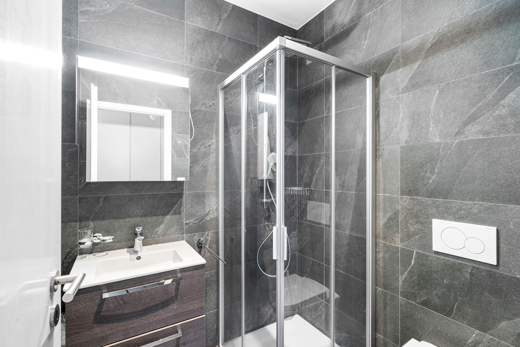 Salle d’eau moderne avec douche vitrée, carrelage effet pierre et meuble vasque contemporain