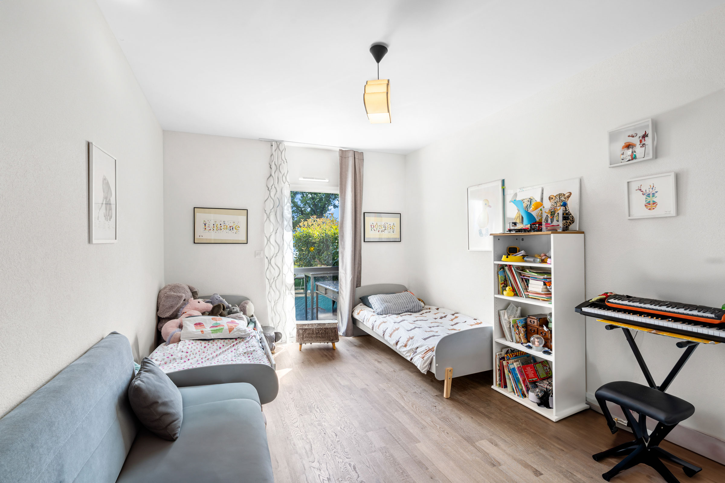 Chambre d’enfant lumineuse avec deux lits, bibliothèque et jouets