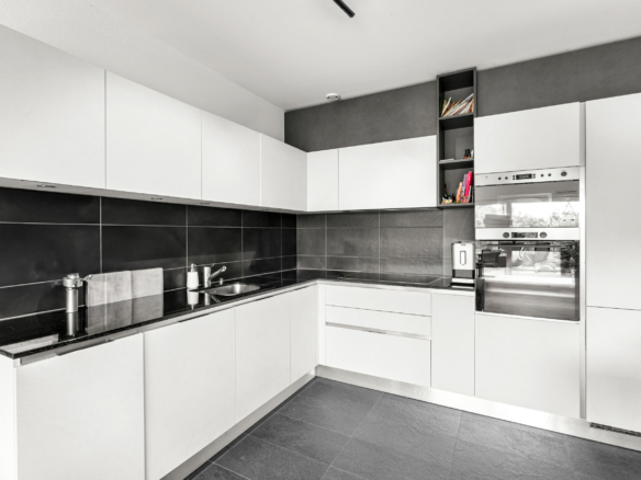 Cuisine blanche contemporaine en angle avec électroménager encastré et plan de travail noir