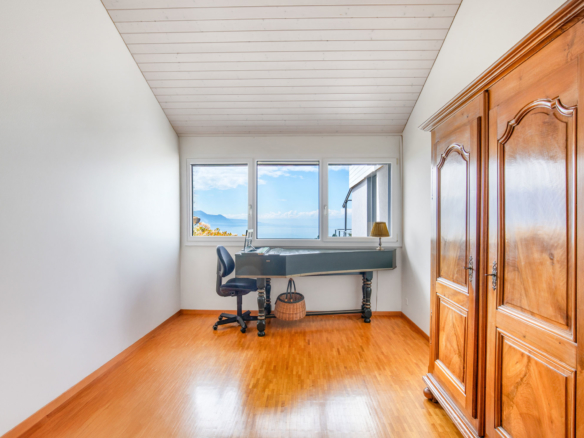 Pièce lumineuse avec bureau et grande armoire, vue dégagée sur le lac Léman.