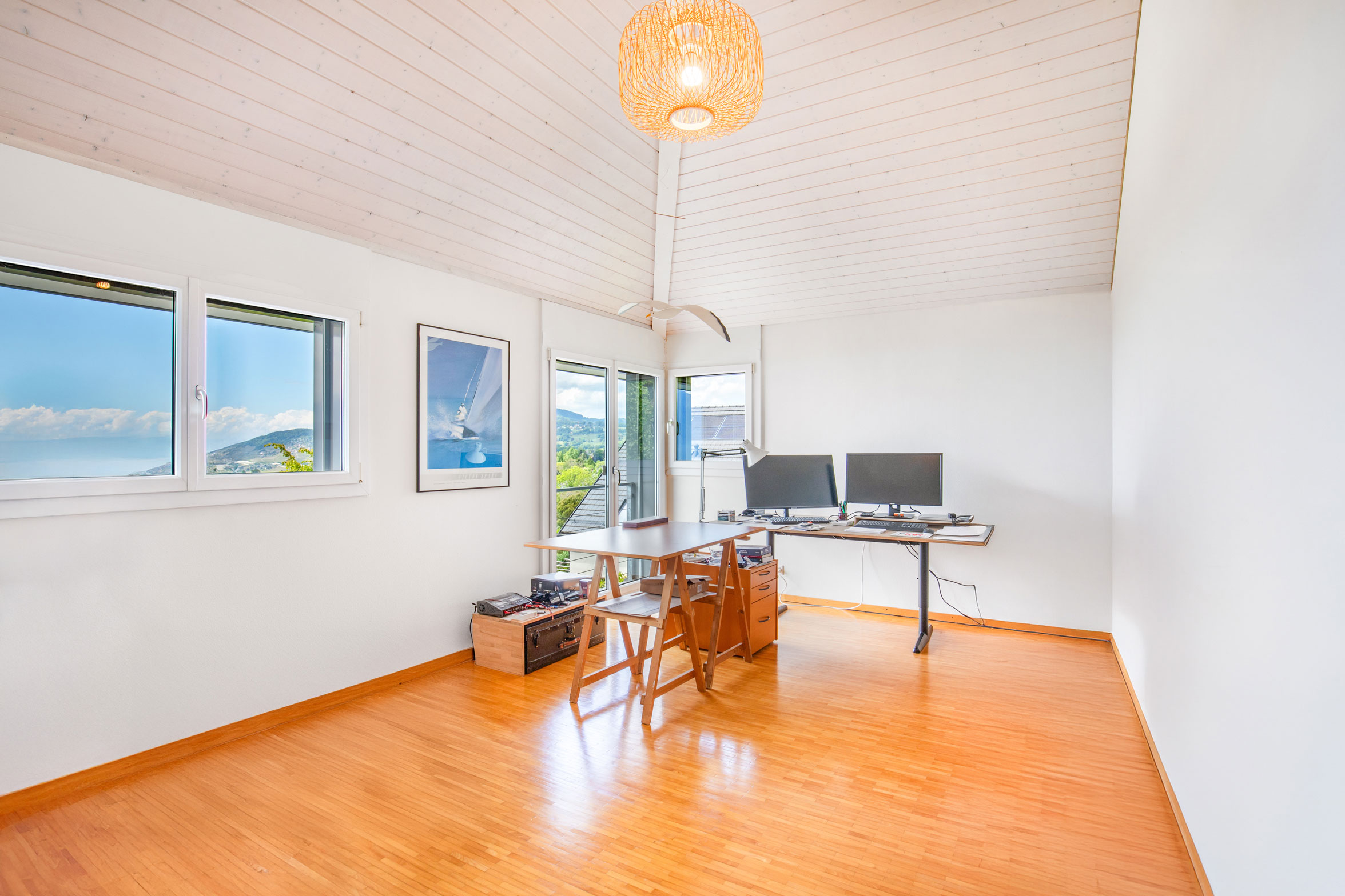 Grand bureau sous toiture avec deux postes de travail, parquet et vue lac.