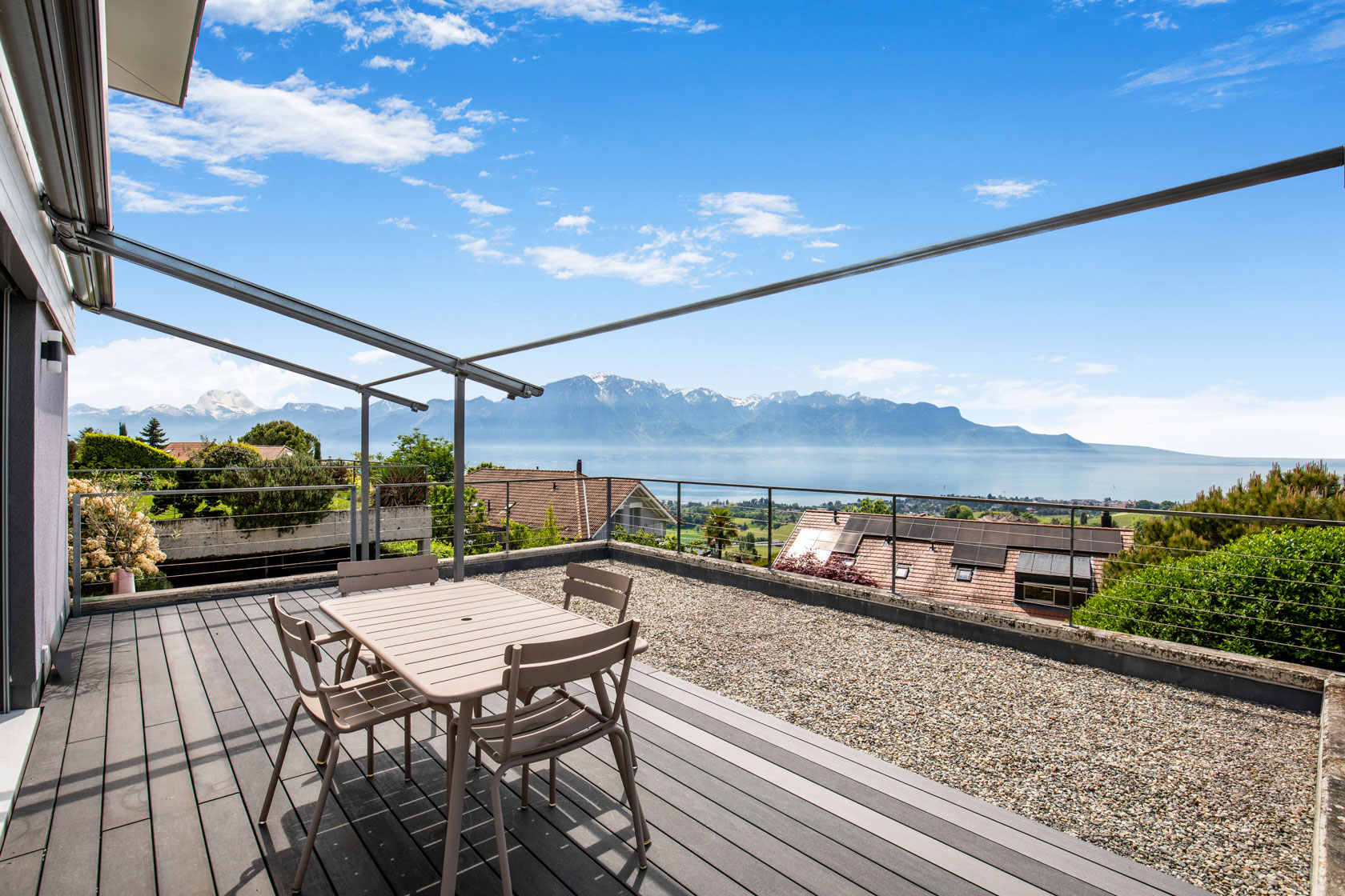 Terrasse avec table à manger et vue panoramique sur le lac Léman et les Alpes.