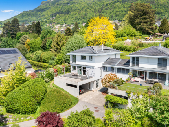 Façade d’une villa contemporaine avec terrasse, garage et jardin arboré