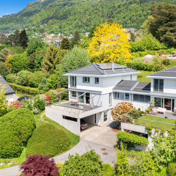 Façade d’une villa contemporaine avec terrasse, garage et jardin arboré