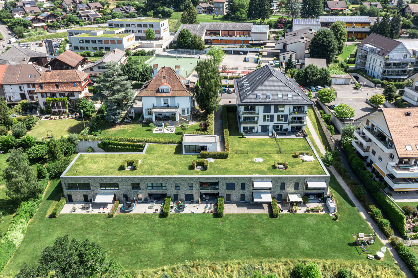 Vue aérienne d’un ensemble résidentiel moderne à toits plats végétalisés au cœur de Saint-Légier