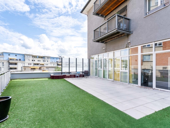 Terrasse ensoleillée attenante au salon avec sol en dalles et gazon synthétique