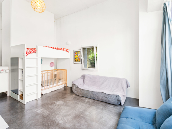 Chambre lumineuse avec lit mezzanine, espace canapé et grande hauteur sous plafond