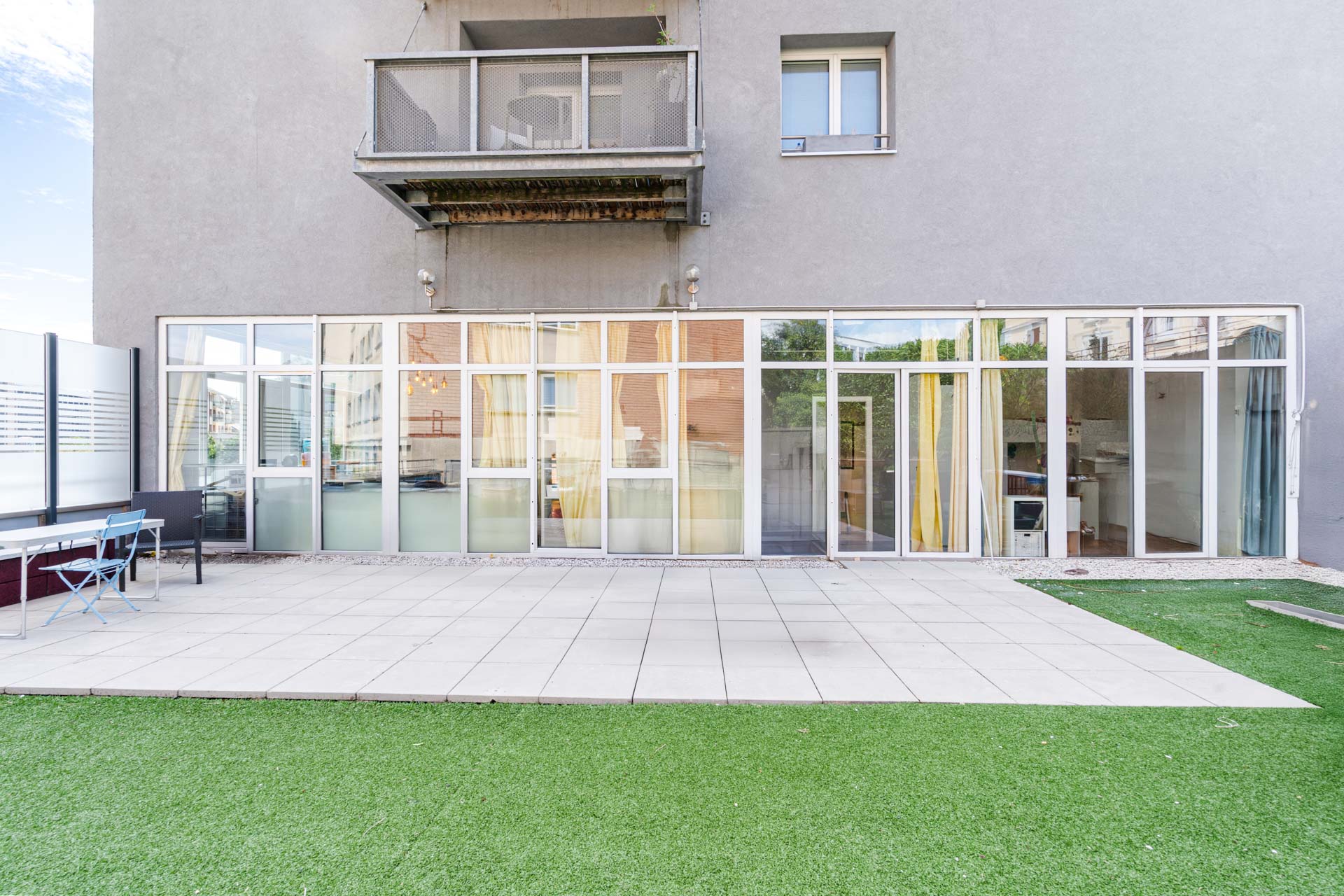 Spacieuse terrasse privative avec pelouse synthétique et vue dégagée sur les immeubles environnants à Lausanne