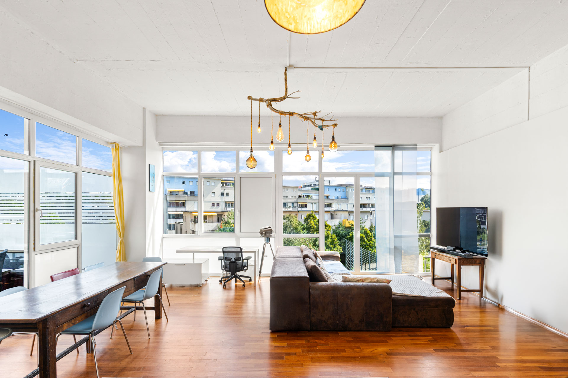 Salon spacieux et lumineux avec parquet, canapé d’angle et grandes baies vitrées