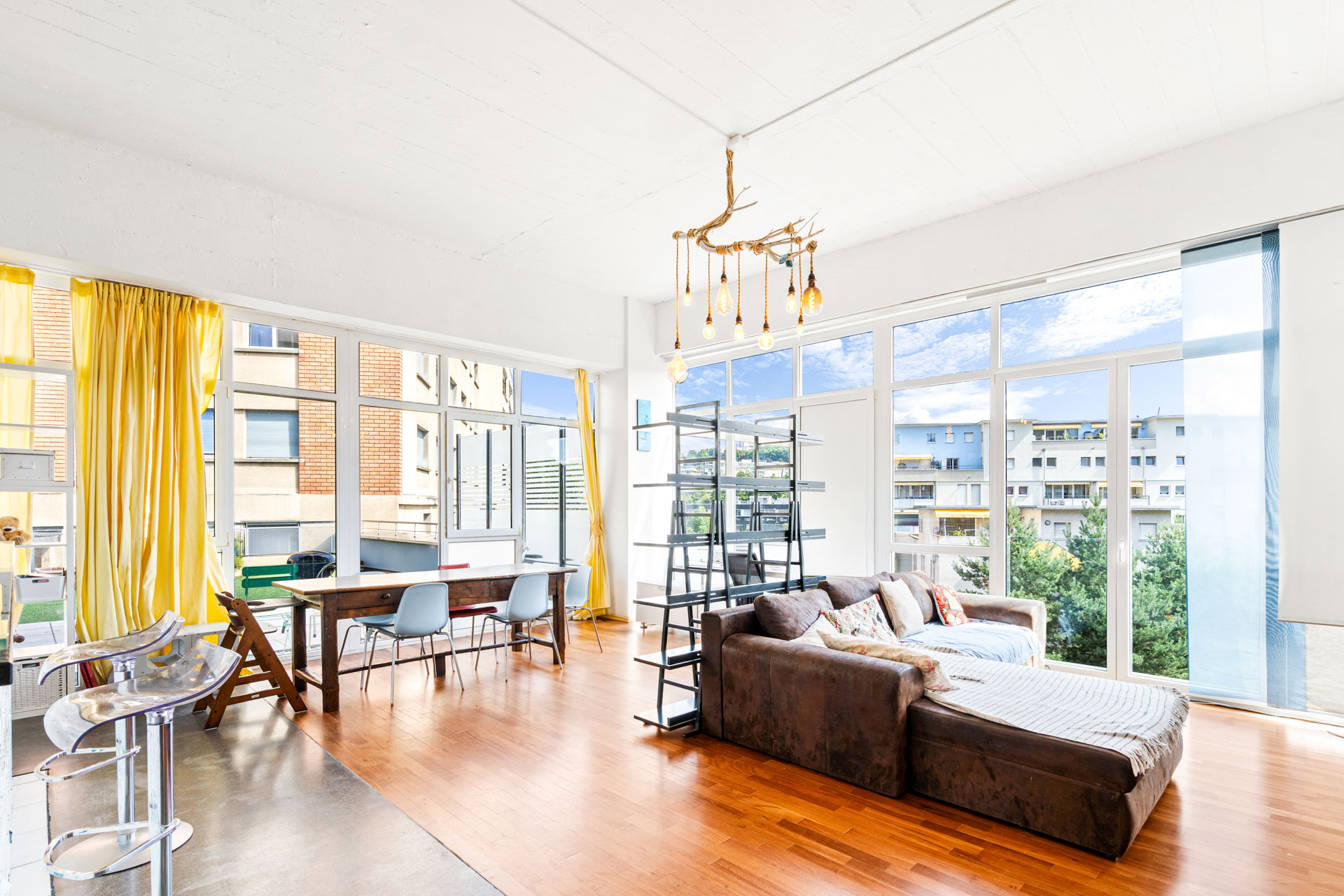 Salon design avec parquet, baies vitrées et rideaux jaunes