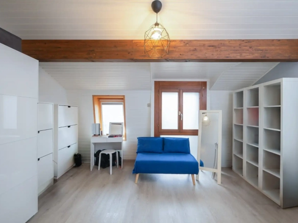 Bureau lumineux avec canapé bleu, bibliothèque et poutre apparente