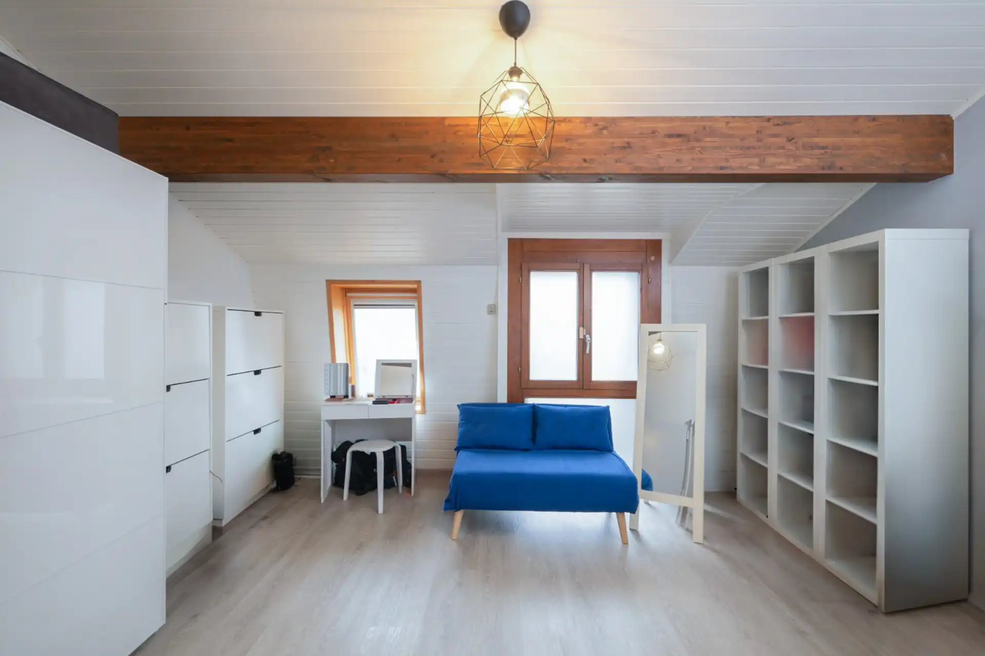 Bureau lumineux avec canapé bleu, bibliothèque et poutre apparente