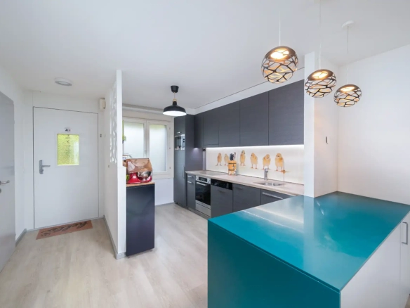 Cuisine moderne ouverte avec ilot central turquoise et électroménagers encastrés