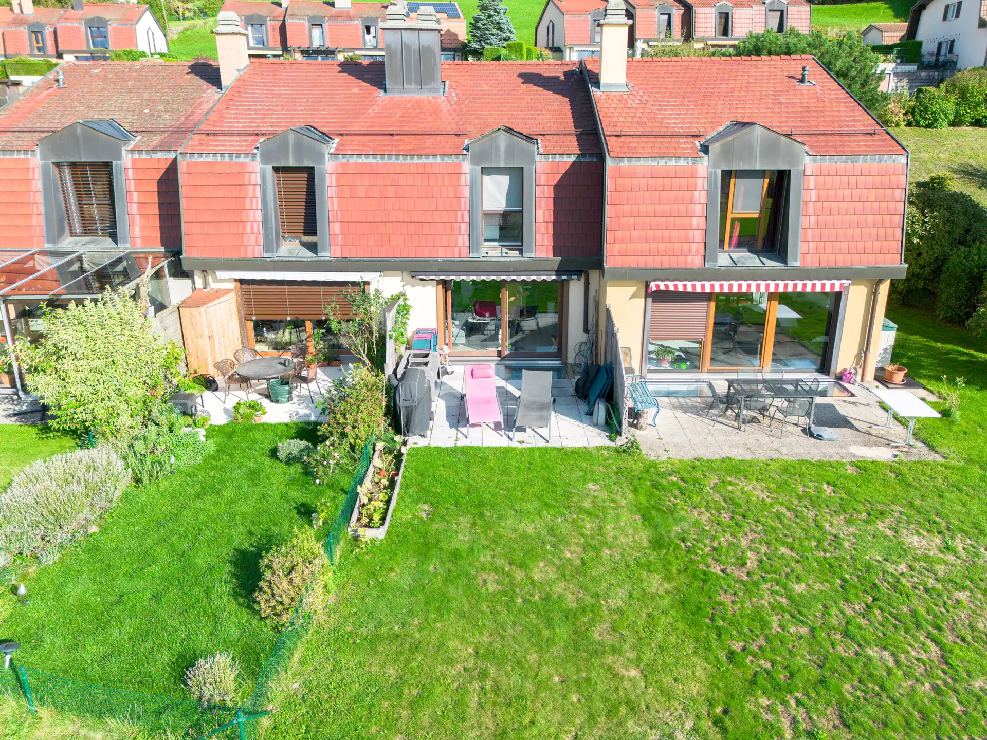 Façade arrière de la maison avec terrasse aménagée et grand jardin