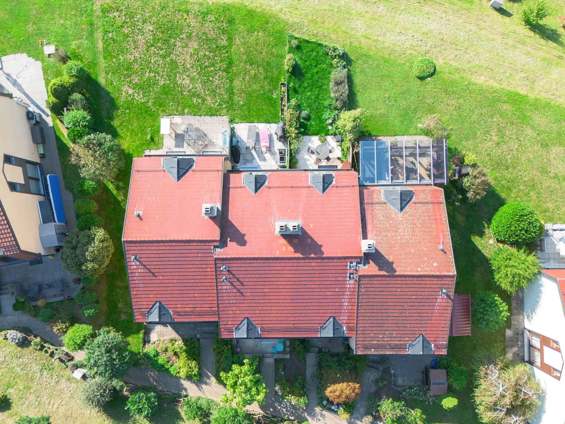 Vue aérienne de la maison avec toiture rouge et grand jardin verdoyant