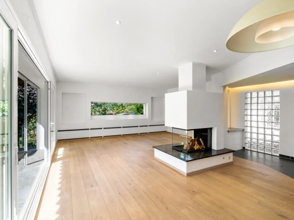 salon spacieux avec cheminée centrale et parquet en bois.