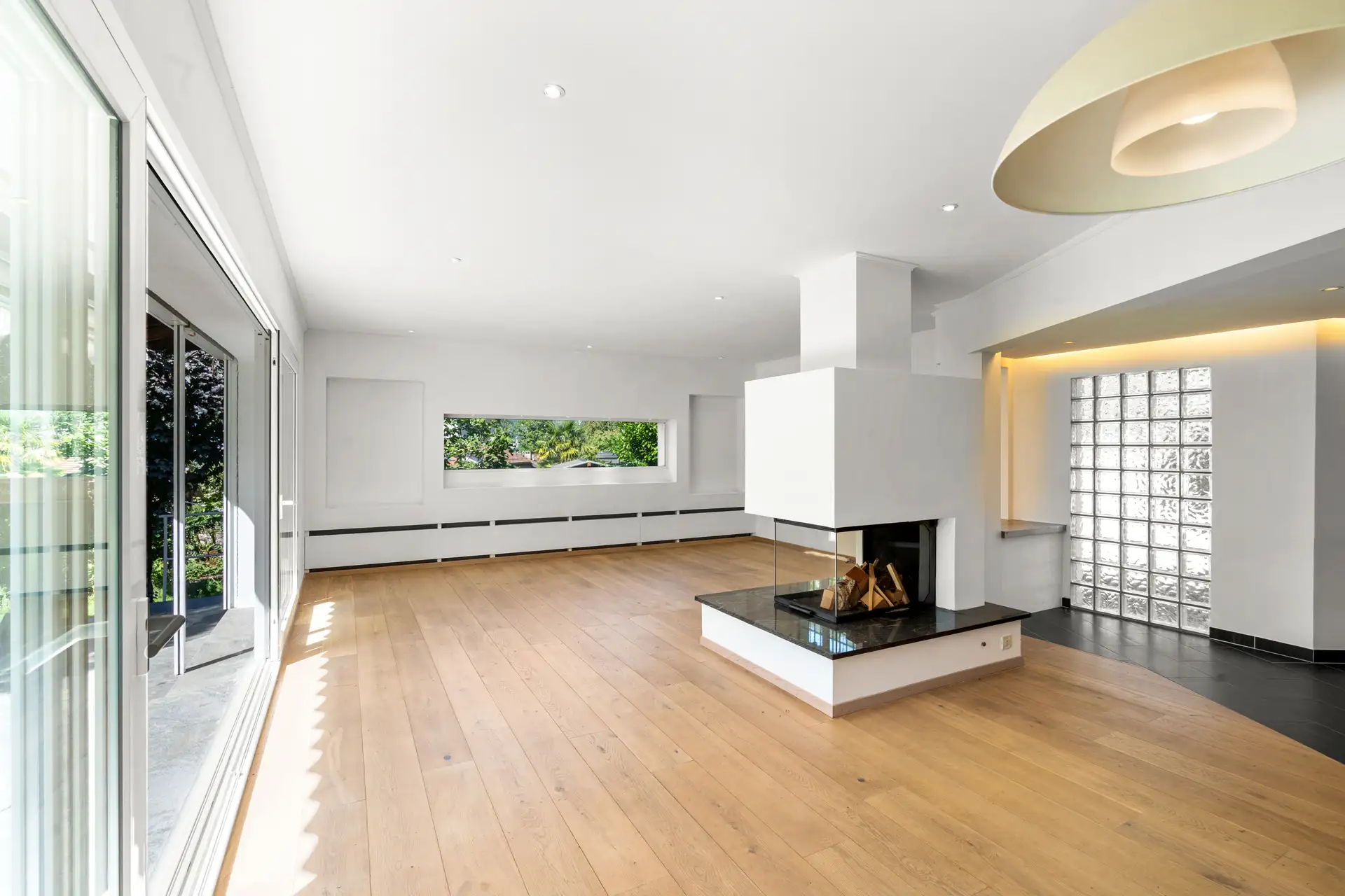salon spacieux avec cheminée centrale et parquet en bois.