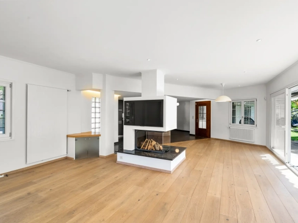 salon spacieux avec cheminée centrale et parquet en bois.