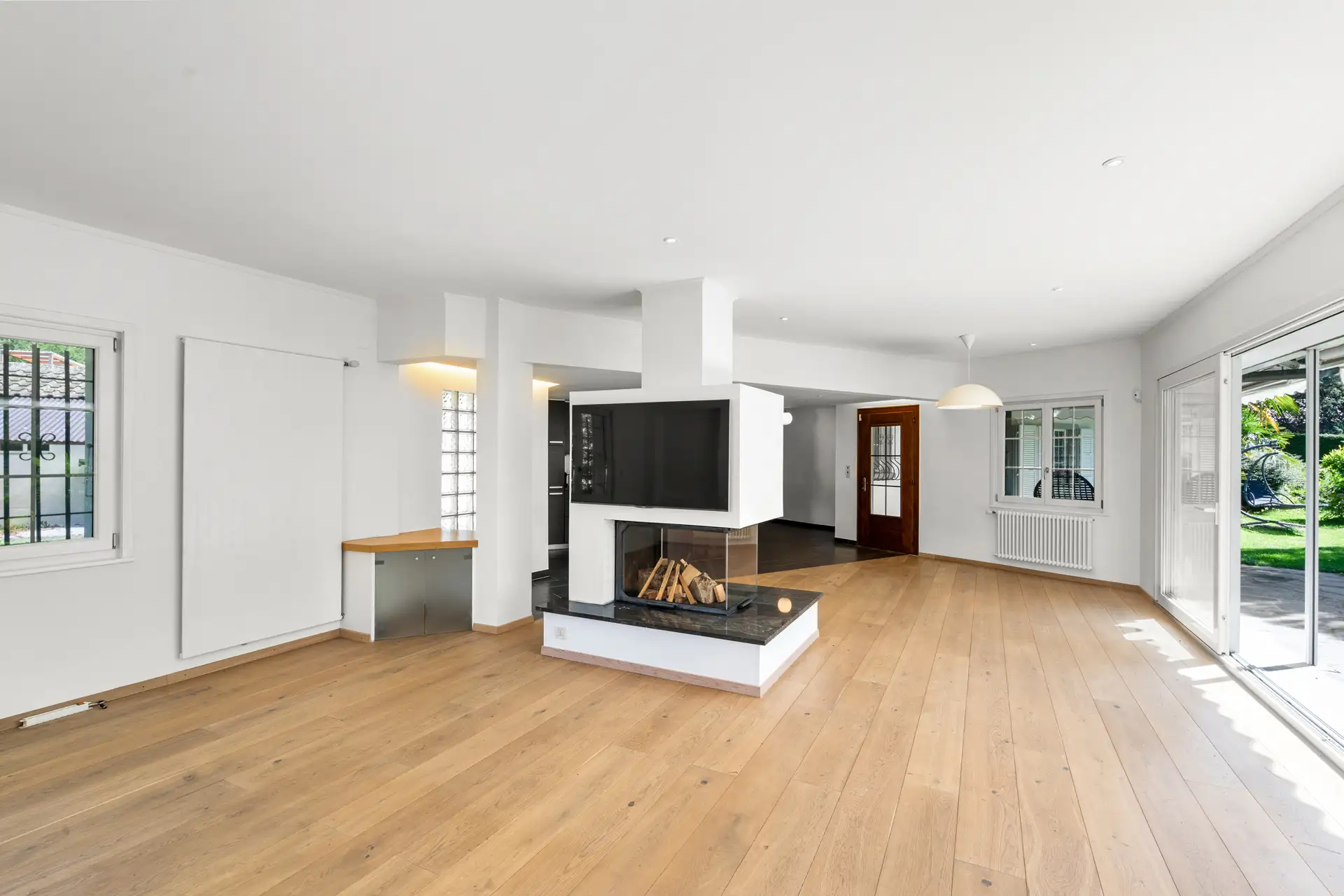 salon spacieux avec cheminée centrale et parquet en bois.