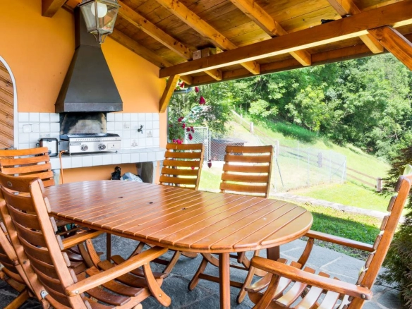 Terrasse couverte avec barbecue et table en bois à Blonay.