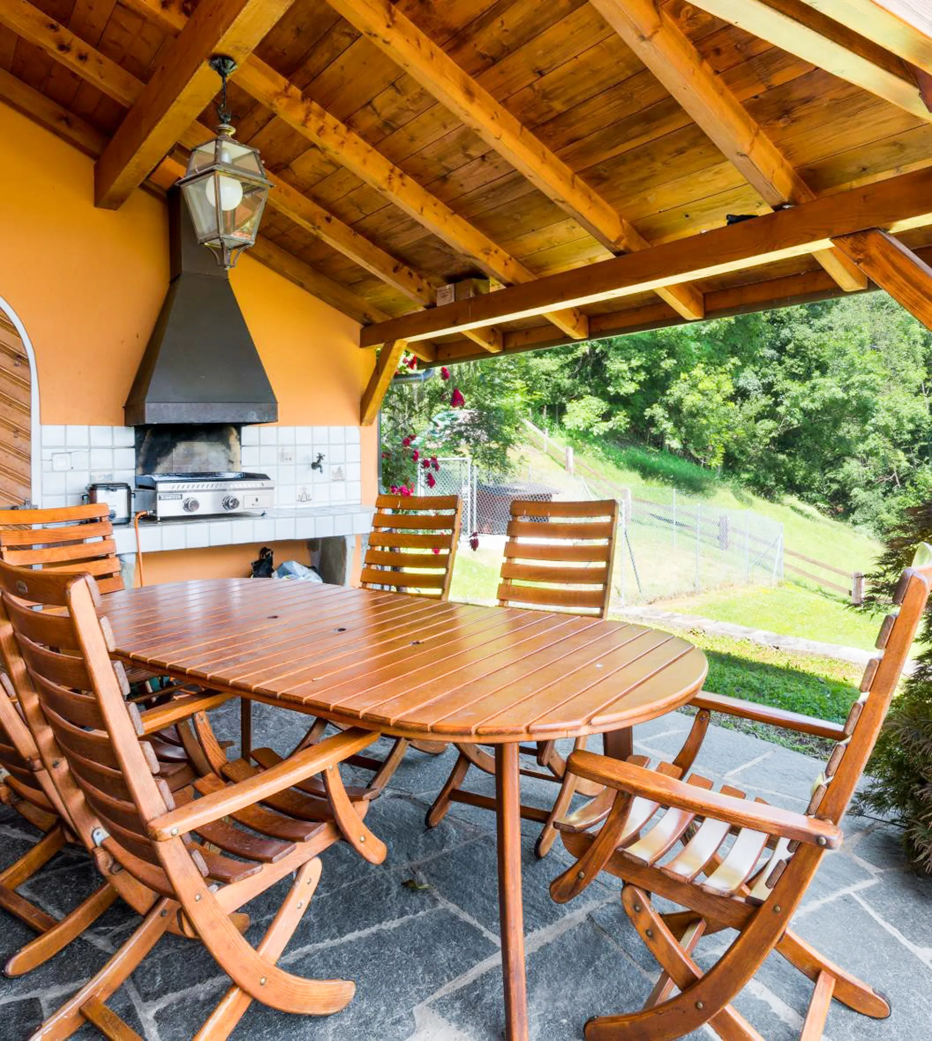 Terrasse couverte avec barbecue et table en bois à Blonay.