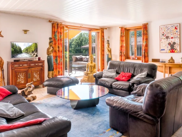 Salon lumineux avec cheminée et grandes fenêtres à Blonay.