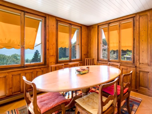 Salle à manger conviviale en bois avec grandes fenêtres.