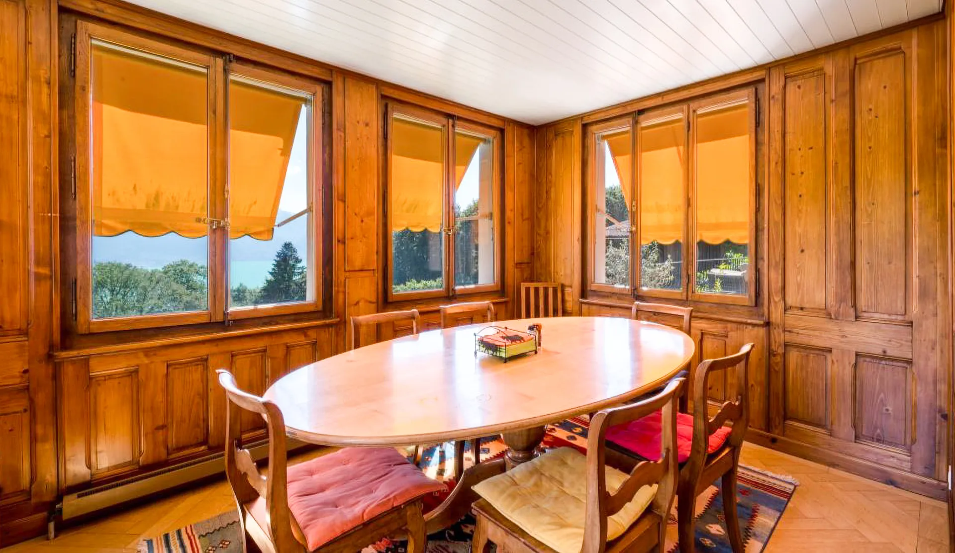 Salle à manger conviviale en bois avec grandes fenêtres.