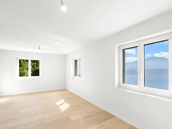 Chambre avec parquet clair et grande fenêtre sur la verdure