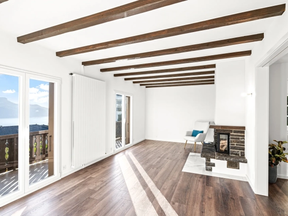 Grand séjour avec poutres apparentes, parquet et cheminée à Chernex