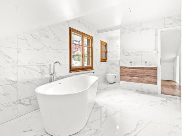 Salle de bain moderne avec baignoire design et vue sur l’extérieur à Chernex