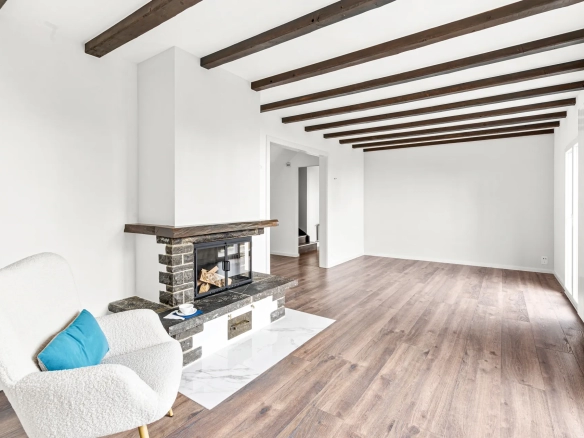 Salon rénové avec cheminée en pierre et poutres en bois