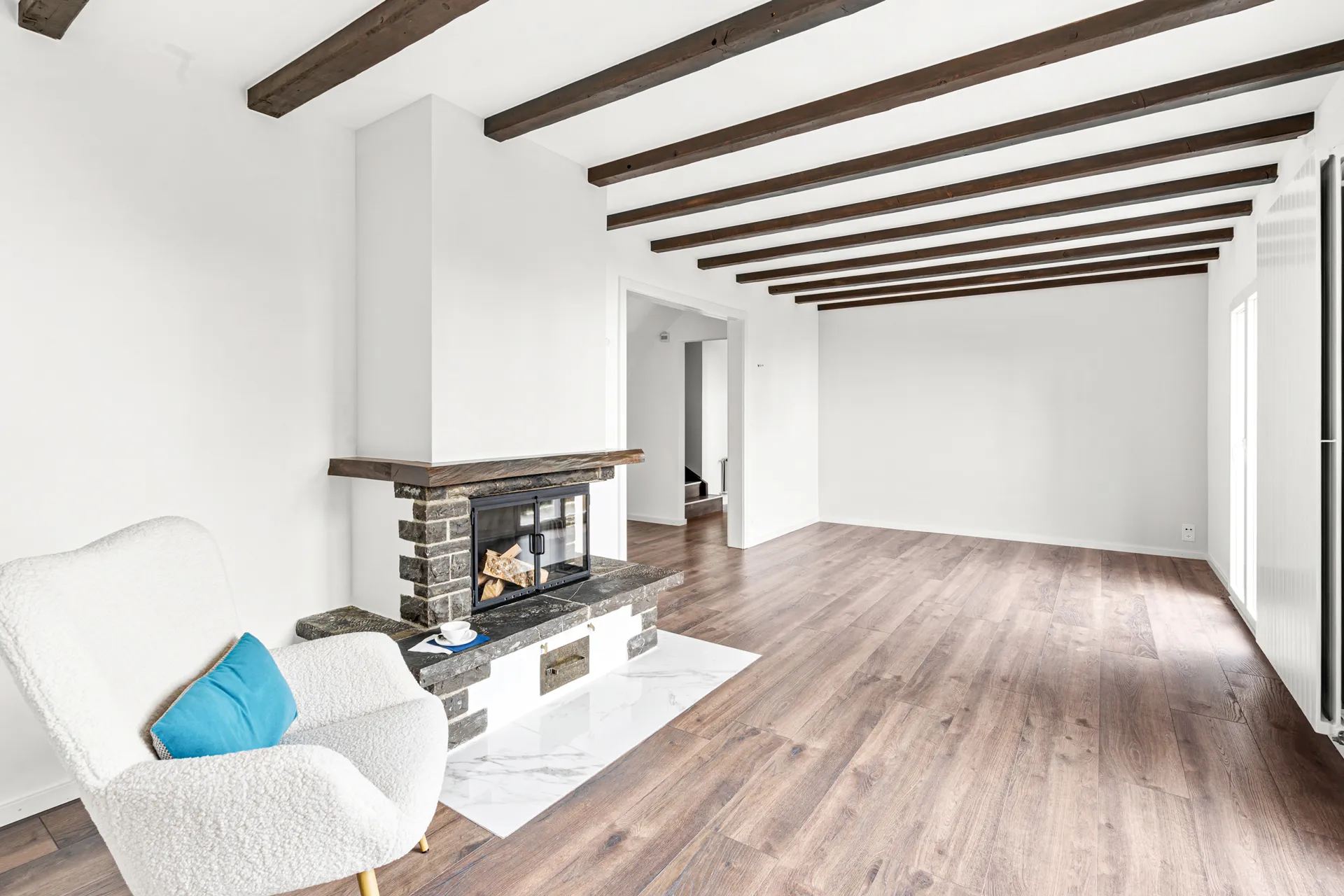 Salon rénové avec cheminée en pierre et poutres en bois