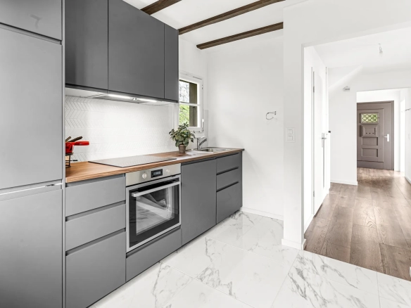 Cuisine ouverte avec armoires grises et plan de travail en bois