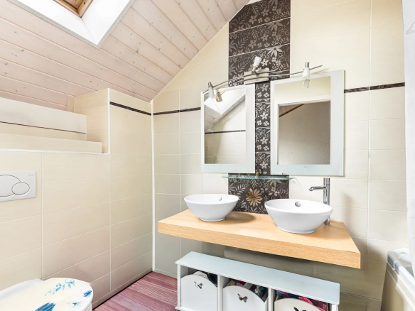 Salle de bain moderne sous combles avec double vasque et douche italienne.