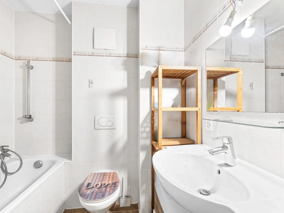 Salle de bain moderne avec baignoire, lavabo et étagères en bois.