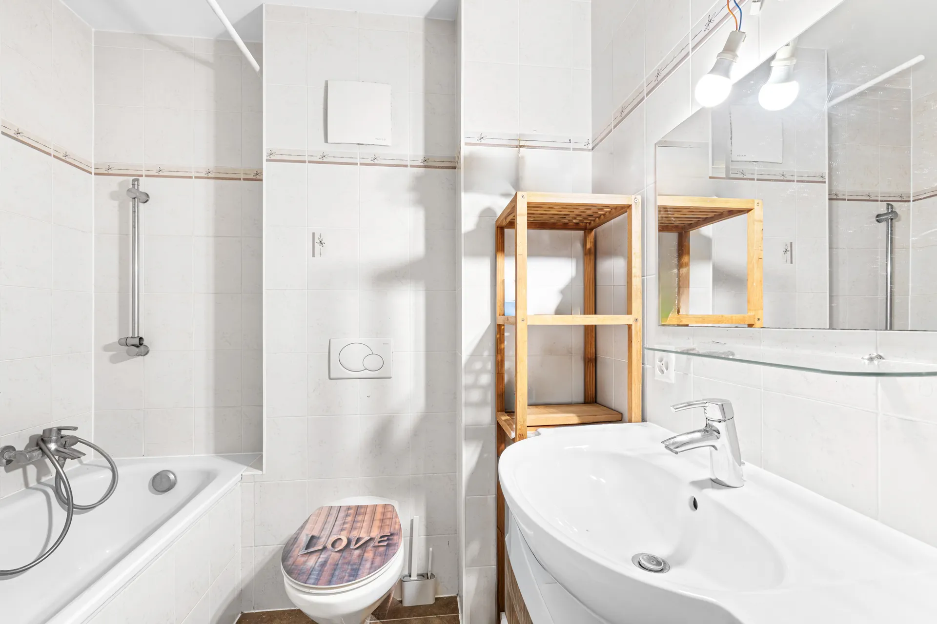 Salle de bain moderne avec baignoire, lavabo et étagères en bois.