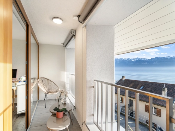 Petit espace détente avec fauteuil, baies vitrées et vue sur le lac Léman.