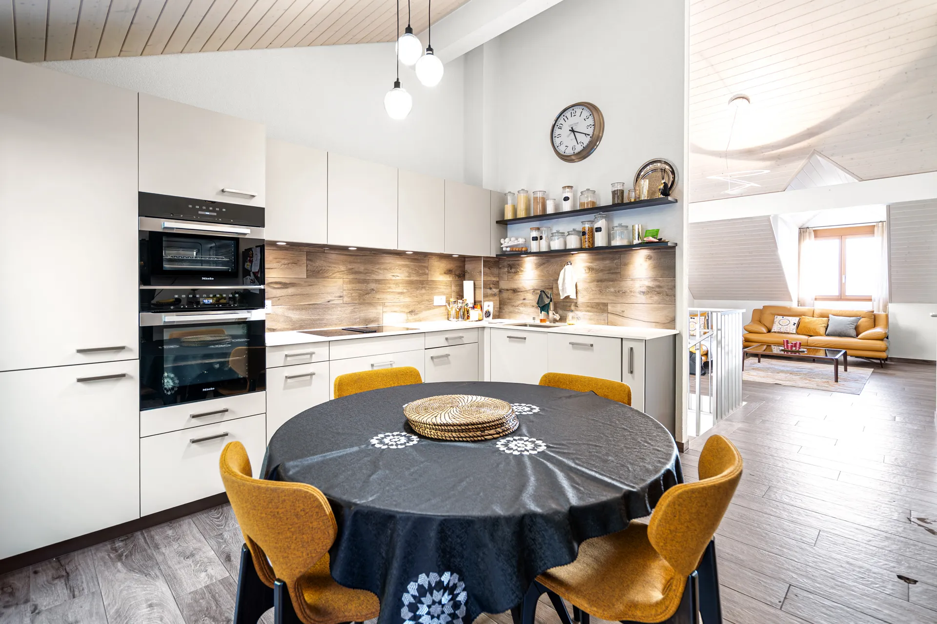 maison-vendre-vuelace-chexbres-immobilier 14 Vue d’ensemble sur la cuisine ouverte et le séjour avec poutres et parquet clair.